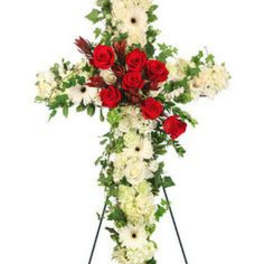 Standing cross-shaped spray of white flowers with red roses on a metal easel