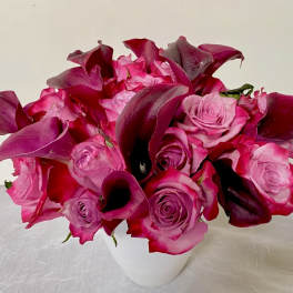 Pink roses and dark magenta calla lilies in a white vase