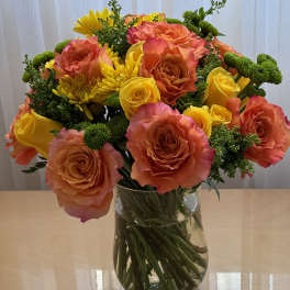 Bouquet of orange and yellow roses with yellow chrysanthemums in a glass vase