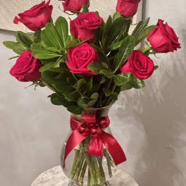 Bouquet of red roses in a glass vase with a pink ribbon