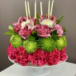 Round floral cake with pink and white blooms and sparkler candles