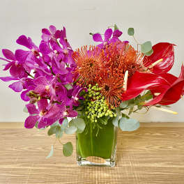 Bright orchid and anthurium arrangement in a glass vase