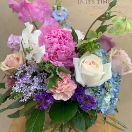 Mixed bouquet of pink, white, blue, and purple flowers in a glass vase