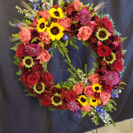 Circular floral wreath with red, pink, yellow, and purple flowers on a stand