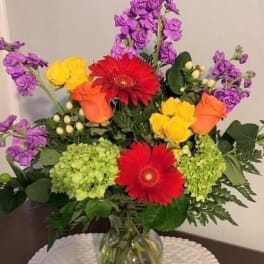 Colorful mixed bouquet in a clear glass vase with gerbera daisies and roses