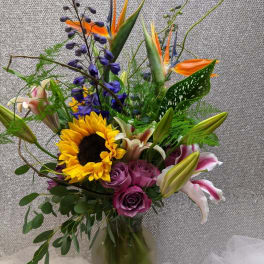 Mixed bouquet with sunflowers, roses, lilies, and bird of paradise in a vase