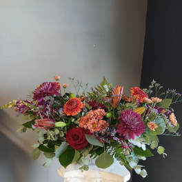 Mixed bouquet of roses, chrysanthemums, and lilies in a white vase