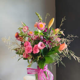 Pink and orange mixed bouquet in a glass vase with a ribbon