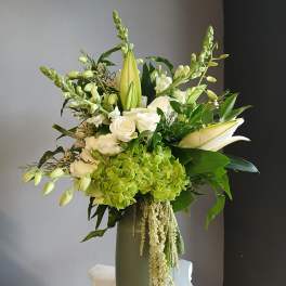 White and green floral arrangement in a tall vase