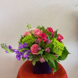 Bouquet of pink roses and purple flowers in a dark vase