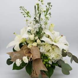White lilies and roses arranged in a burlap-wrapped box