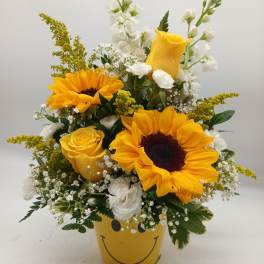 Yellow sunflower and rose arrangement in a smiley-face pot