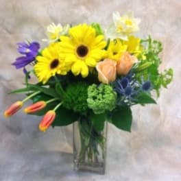 Mixed bouquet of yellow daisies and lilies in a clear glass vase