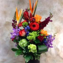 Colorful tropical bouquet in a black vase with bird of paradise and roses