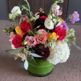 Mixed bouquet of roses, lisianthus, and hydrangea in a green vase