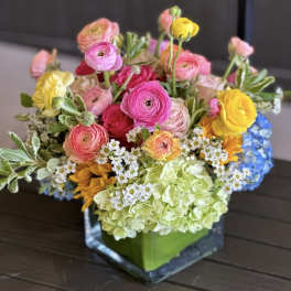 Colorful mixed bouquet in a square glass vase with hydrangea and ranunculus