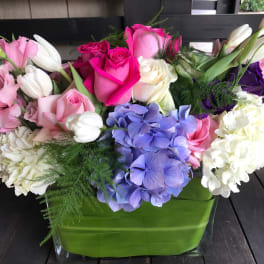 Mixed bouquet of roses, hydrangeas, tulips, and lilies in a green vase