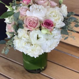 Pink and white roses with white blooms in a green glass vase
