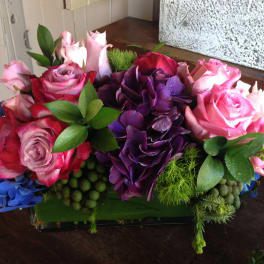 Pink and purple rose arrangement in a low rectangular vase