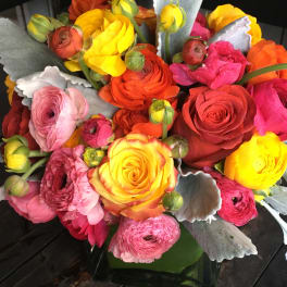 Bright mixed bouquet of ranunculus and roses in a glass vase