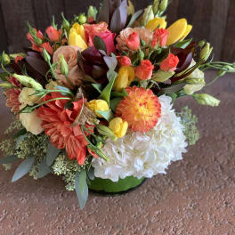 Colorful mixed bouquet with roses, tulips, dahlias, and hydrangea in a green vase