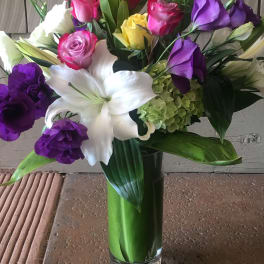 Mixed bouquet of roses, lilies, and hydrangea in a glass vase