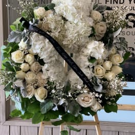 White floral wreath with roses and hydrangeas on an easel