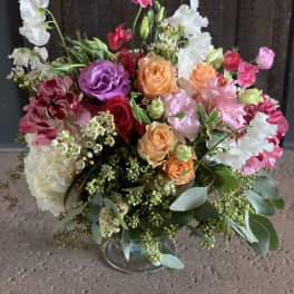 Mixed bouquet of roses, lisianthus, and sweet peas in a glass vase