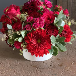 Red and pink flower arrangement in a white vase