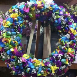 Large rainbow floral wreath with multicolored roses and white filler flowers