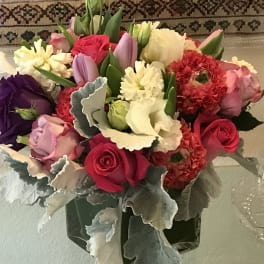 Mixed bouquet of roses, tulips, and carnations in a glass vase