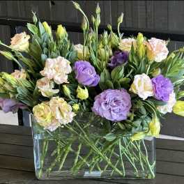 Mixed pastel flowers arranged in a clear rectangular vase