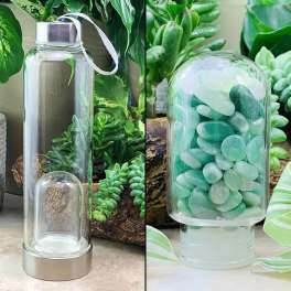 Two glass water bottles with metal lids, one empty and one filled with green stones.