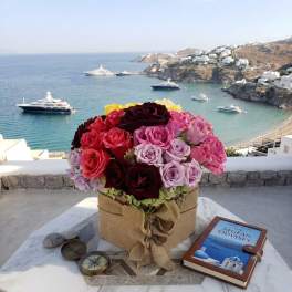 Mixed roses in a burlap-wrapped box on a table overlooking the sea