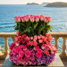 Tiered arrangement of pink roses and purple hydrangeas by the sea