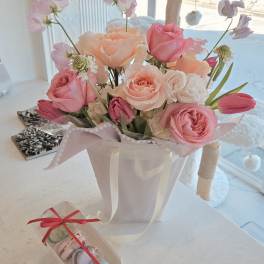 Pink and peach rose bouquet in a white gift bag with a clear macaron box