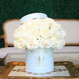 White roses arranged in a round hatbox on a table