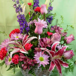 Mixed pink and purple flower arrangement in a white basket