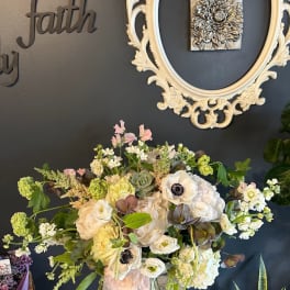 Large mixed floral arrangement in a glass vase with cream and pale pink blooms