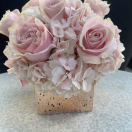 Pink roses and hydrangeas arranged in a square vase
