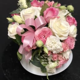 Pink and white rose bouquet with a pink ribbon on a plate