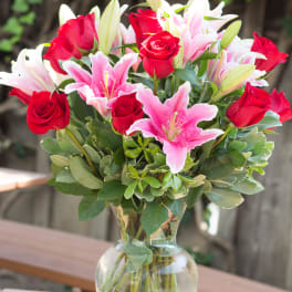 Bouquet of red roses and pink lilies in a clear glass vase