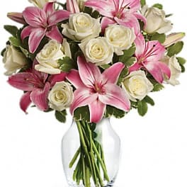 Pink lilies and white roses arranged in a clear glass vase