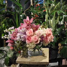 Pink roses and orchids arranged in a clear glass vase