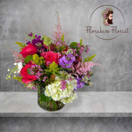 Mixed bouquet of pink, purple, and white flowers in a glass vase