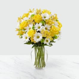 Yellow roses and white daisies in a clear glass vase