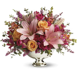 Pink lilies and roses arranged in a silver pedestal vase