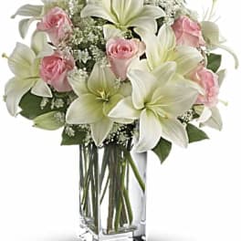 Pink roses and white lilies in a clear glass vase