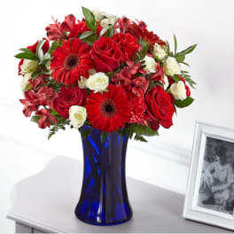 Red and white flower arrangement in a blue vase