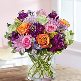 Colorful bouquet of roses and purple flowers in a clear glass vase